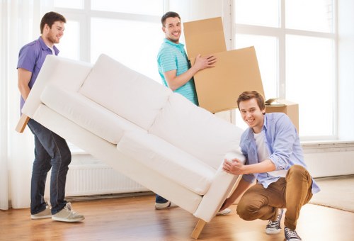 Removal crew carrying furniture through a narrow staircase in a Wandsworth flat